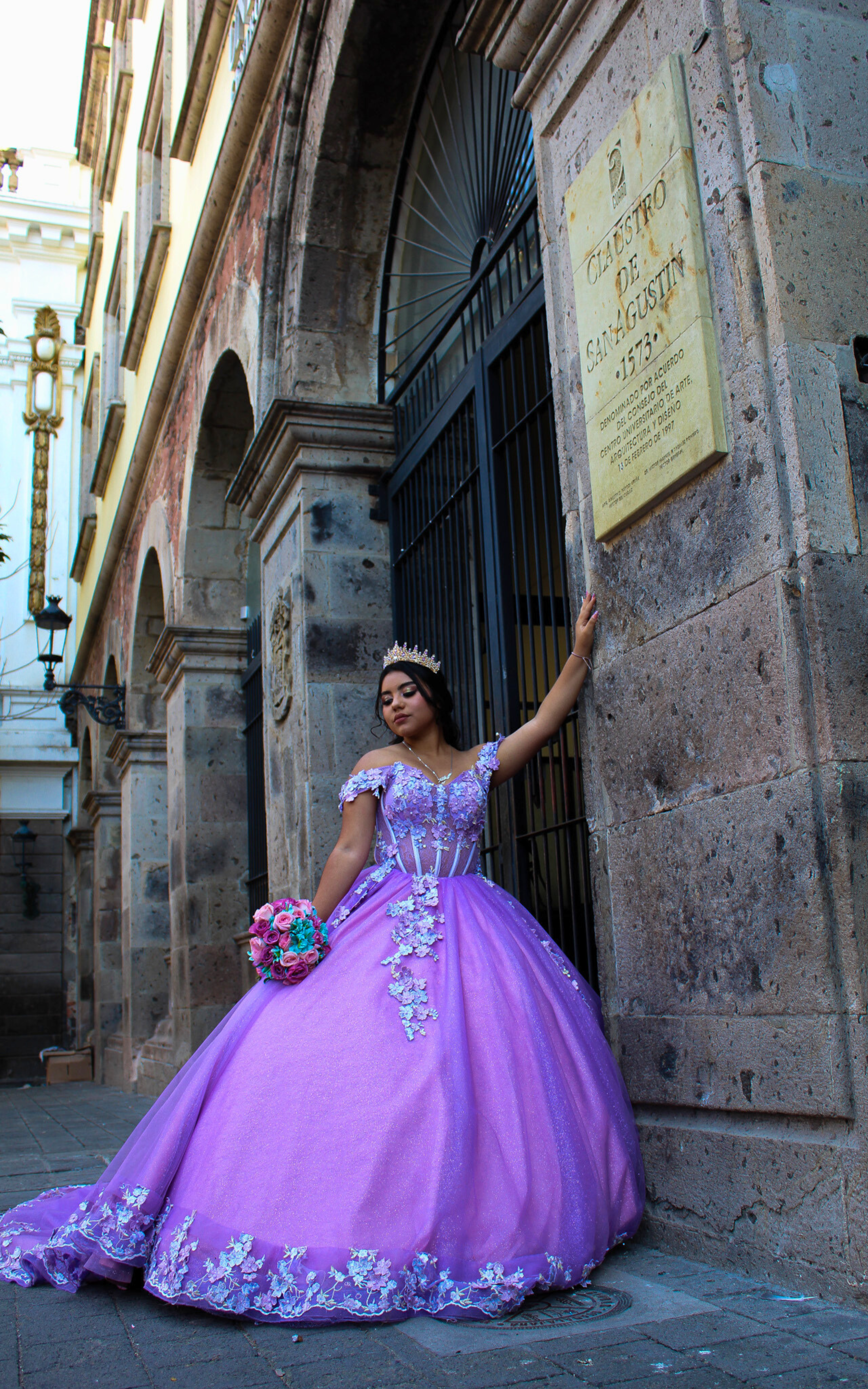 Quinceanera con vestido violeta frente a arquitectura antigua