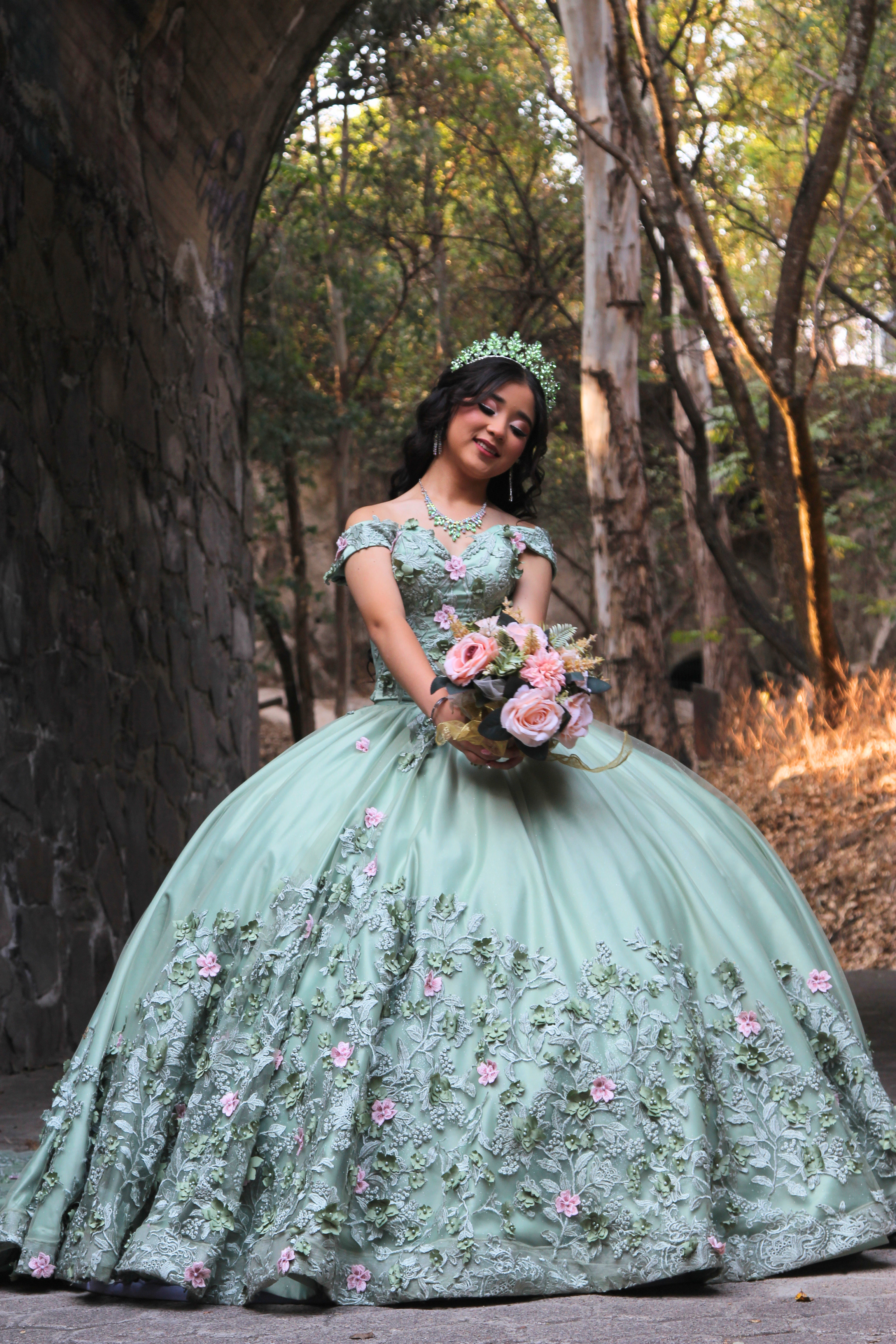 Quinceanera con vestido verde en un bosque
